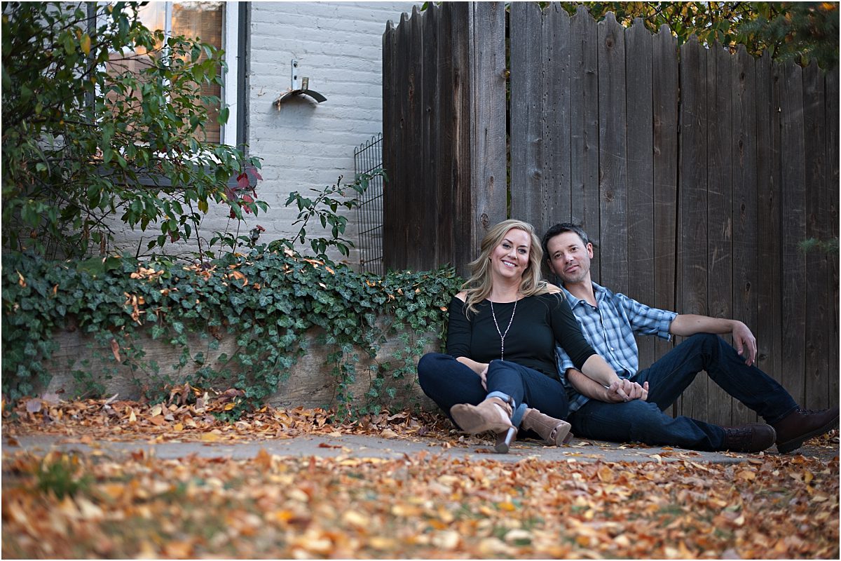 couple sitting on ground with fall leaves, old wood house,clear creek history park, golden colorado engagement session, autumn, l elizabeth events, colorado engagement photography, mountain engagement photographer