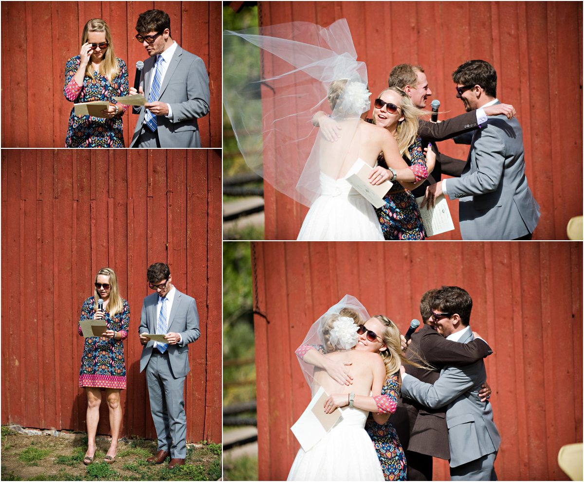 readings, outdoor ceremony in front of rustic red barn at clear creek history park, golden colorado, wedding photographer, colorado wedding planner, bride's veil blowing in the wind, hugging