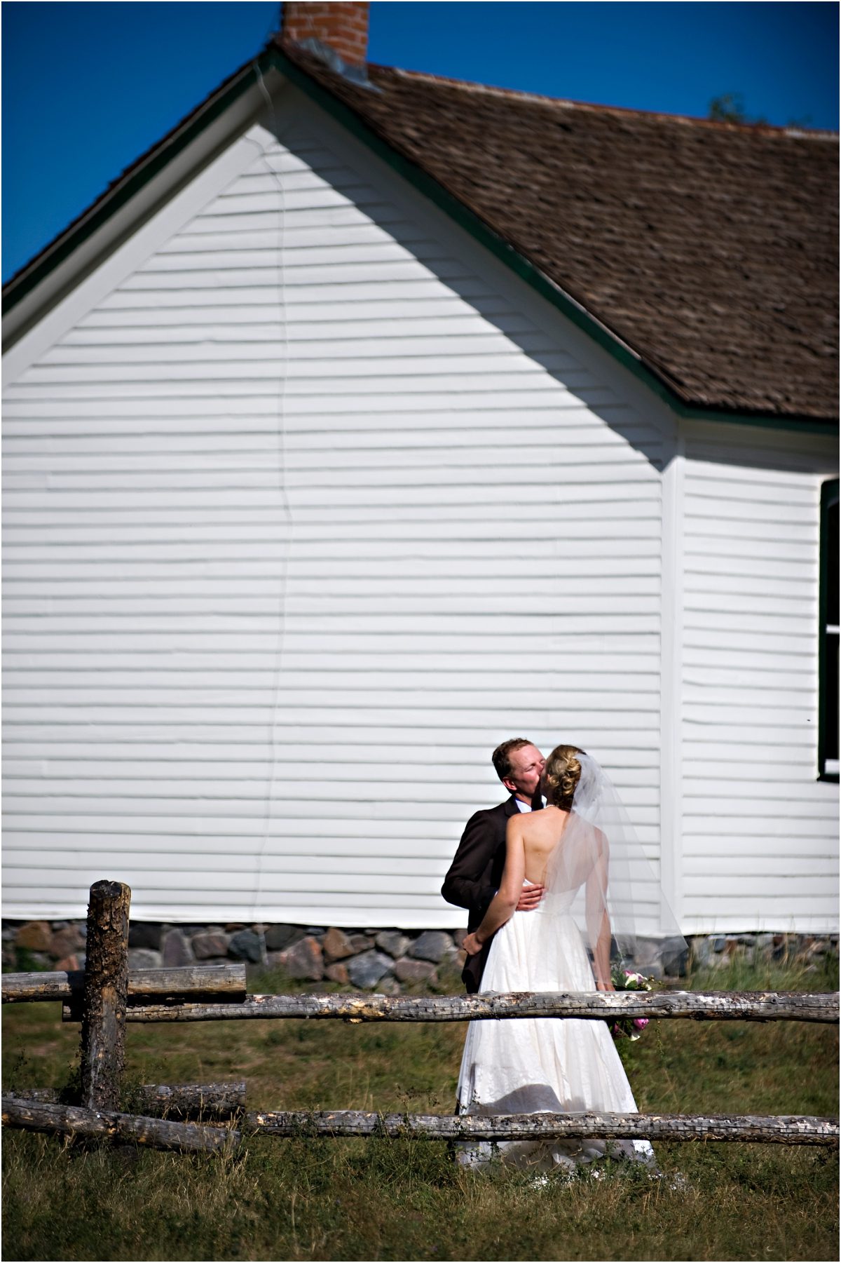bride and groom portraits, kissing in front of rustic white barn,clear creek history park, golden colorado, wedding photographer, colorado wedding planner