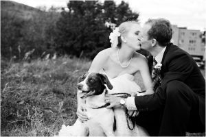 bride and groom kissing with dog in field at clear creek history park, black and white image, golden, colorado wedding photographer, mountain wedding planner