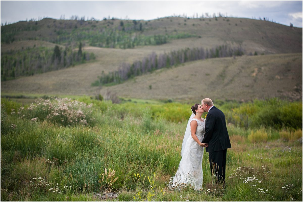 bride and groom kissing in field,C Lazy U Ranch, Granby, Colorado, Rustic Ranch Wedding, Colorado Wedding Planner, Mountain Wedding Photographer