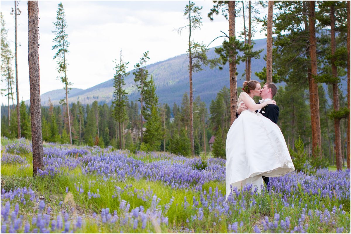 bride and groom in wildflower field among trees, keystone ranch mountain wedding, destination wedding planning