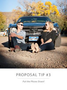 engaged couple sitting by a vintage muscle car
