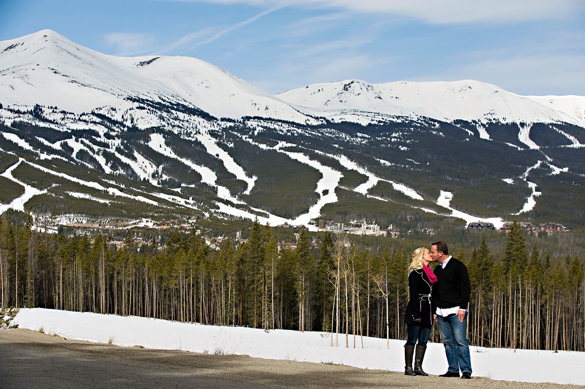 couple kissing behind ski resort, proposal tip 6, destination engagement planning